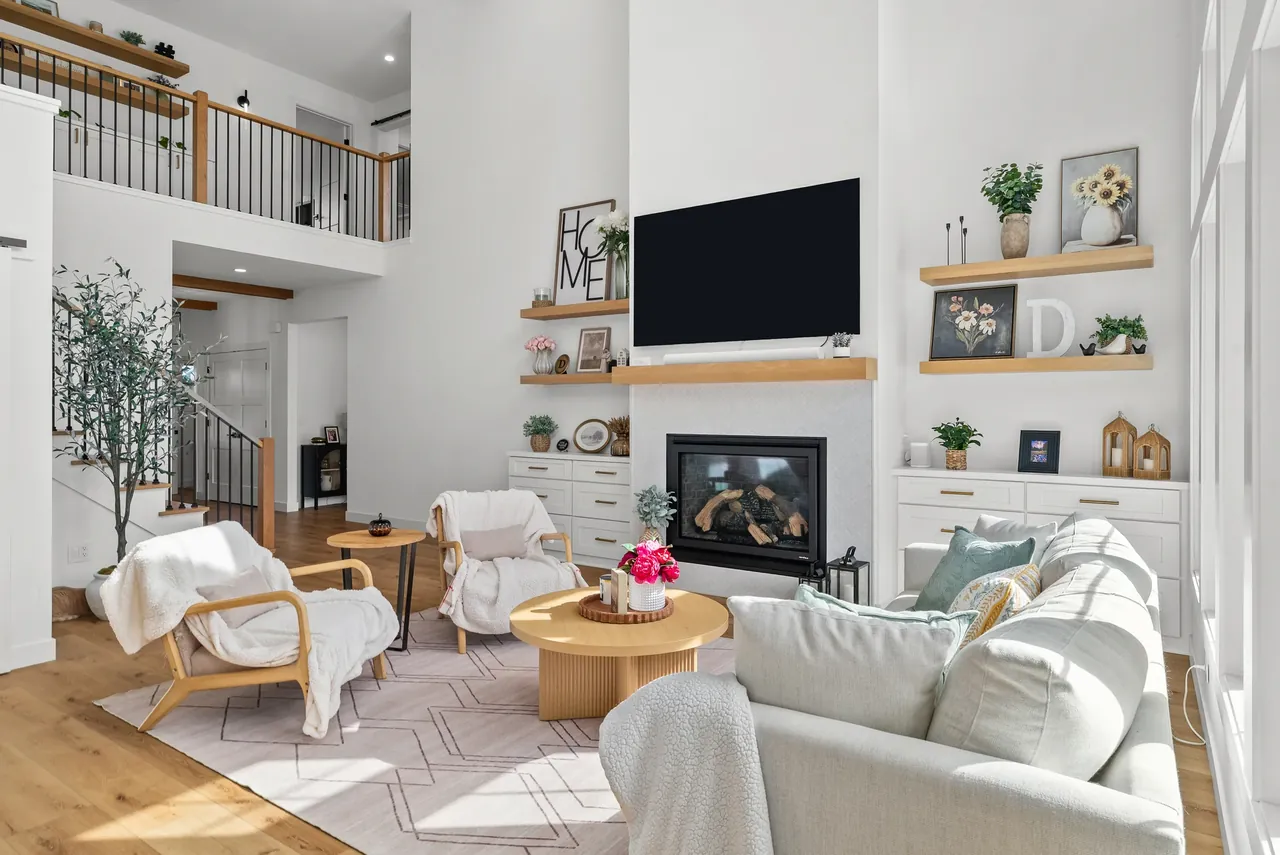 Bright living room with a pale sofa, layered rugs and a fireplace