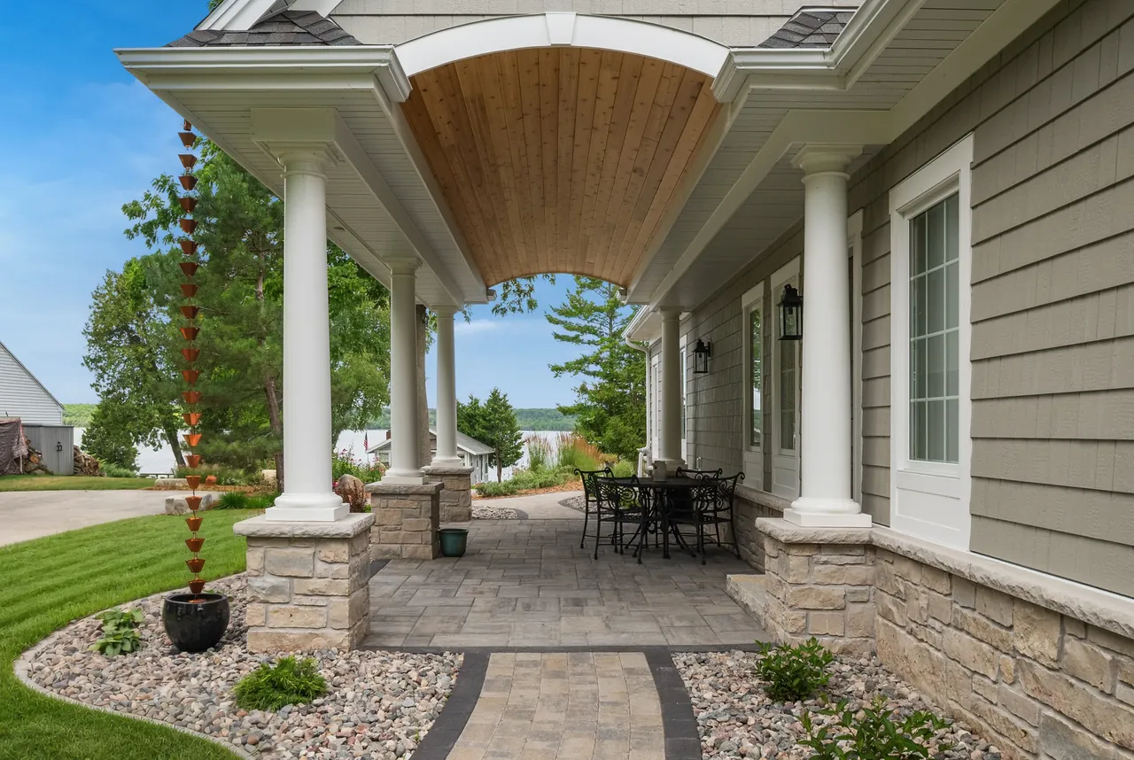 Covered patio with a curved wood ceiling, stone columns and garden seating