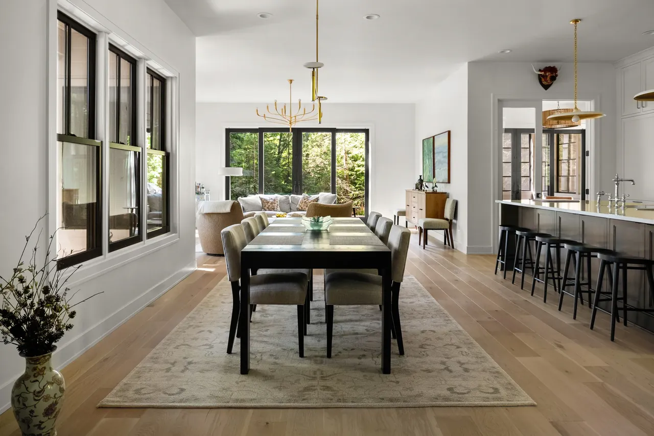 Dining room with a dark table, upholstered chairs and views into a kitchen