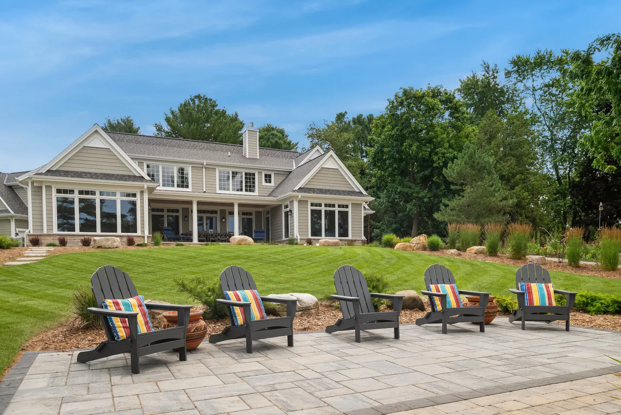 Home with a landscaped patio and Adirondack chairs