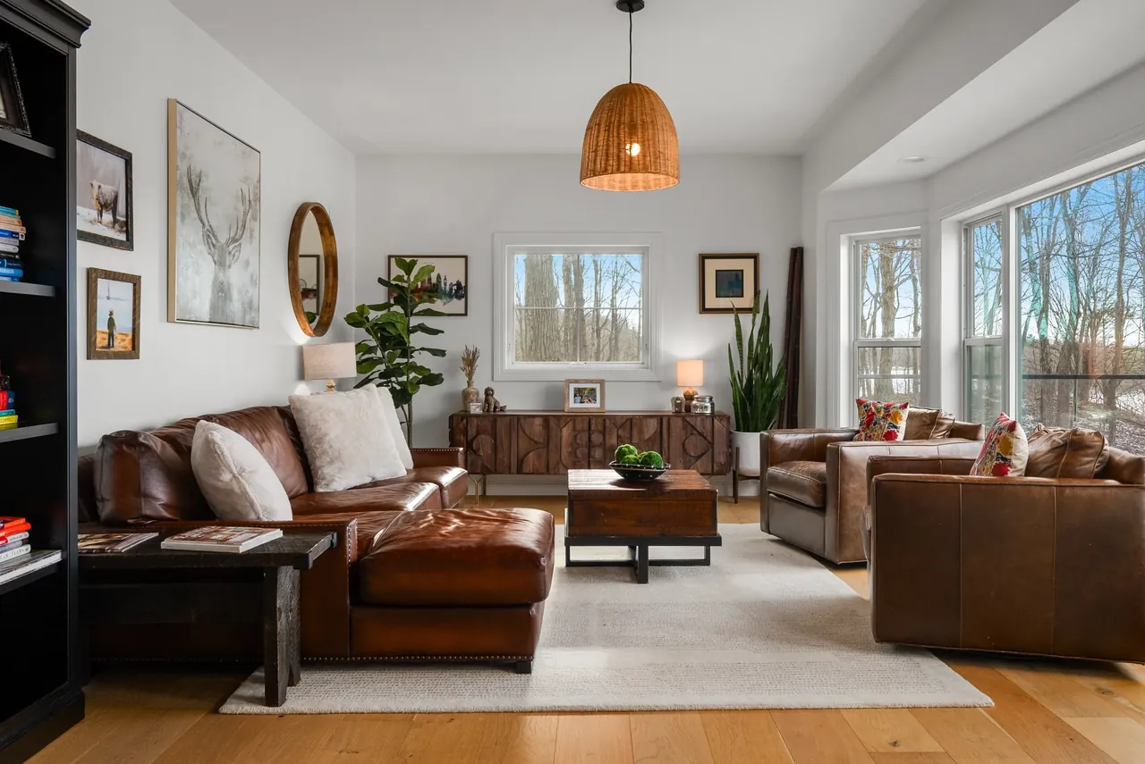 Living room with a brown leather sofa, fireplace and natural light