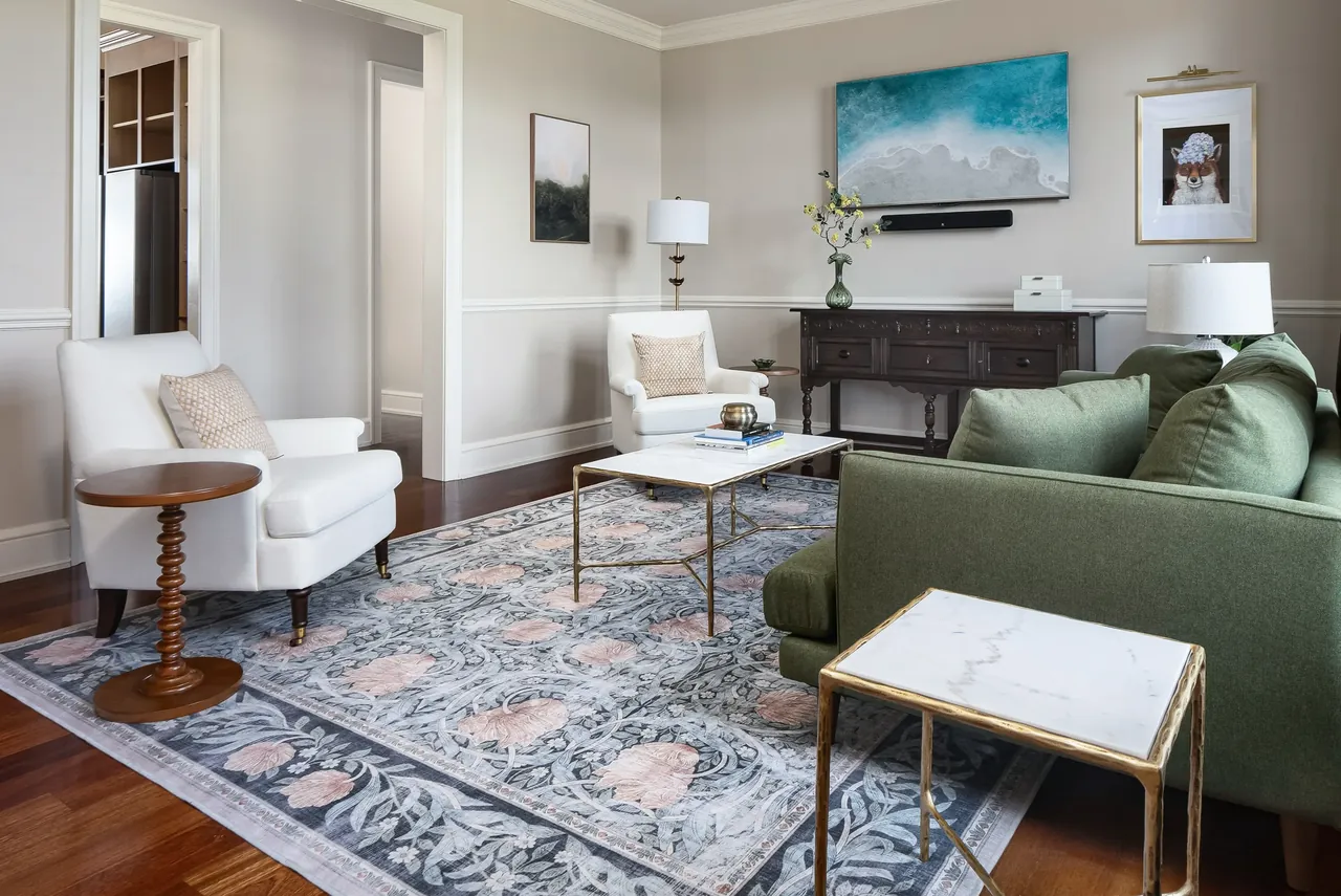 Sitting room with a green sofa, pale armchairs and a patterned rug