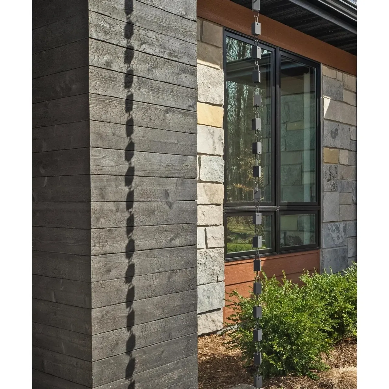 Close view of a stone column, wood siding and glass at an entry