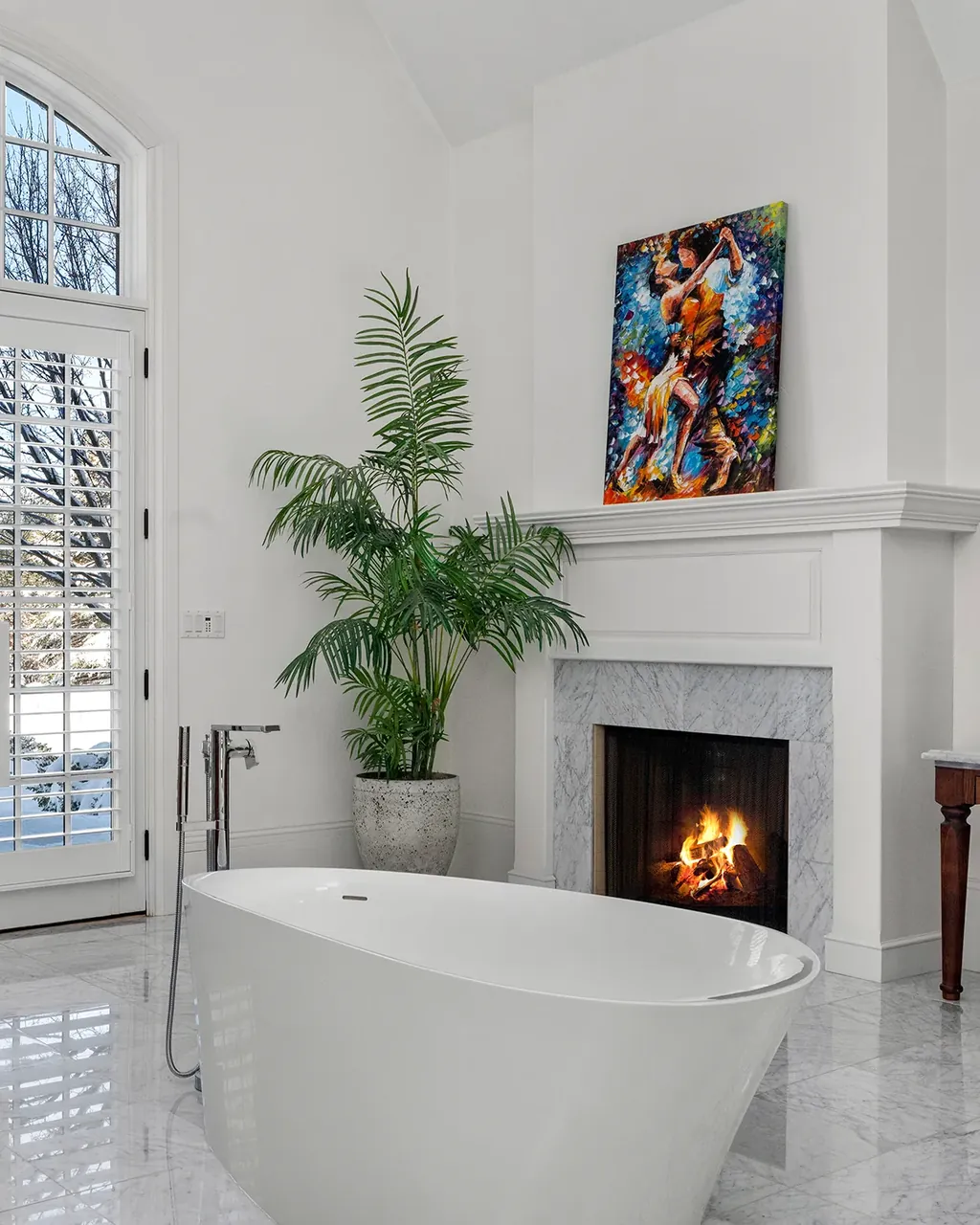 White fireplace with a small fire and colorful framed artwork