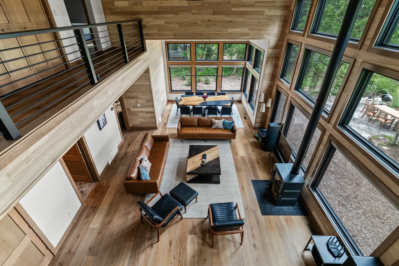 View from a loft into a timber-framed living room with tall windows