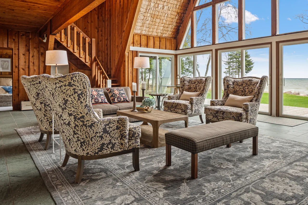 Waterfront lodge lounge with timber beams and patterned armchairs