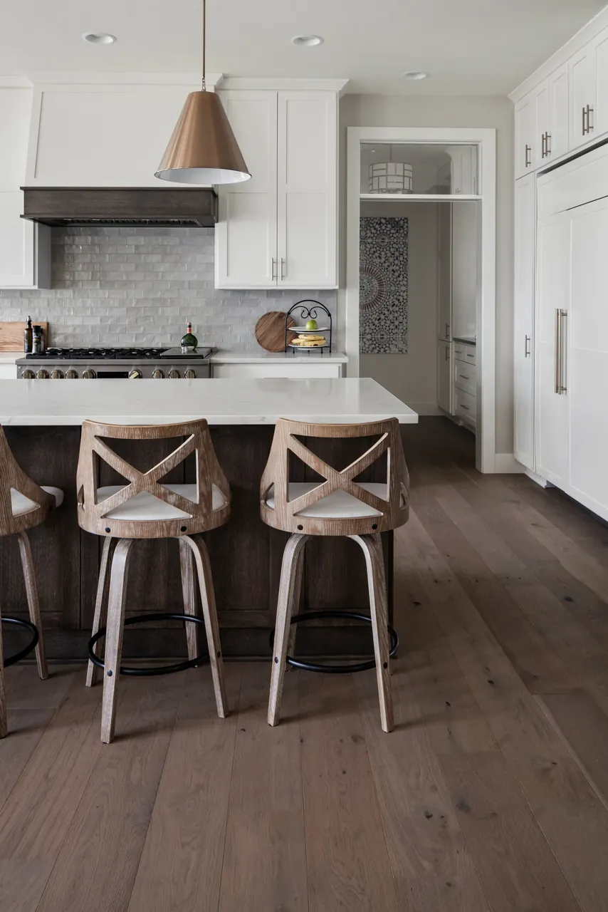 White kitchen with a wood range hood, island seating and dark wood flooring